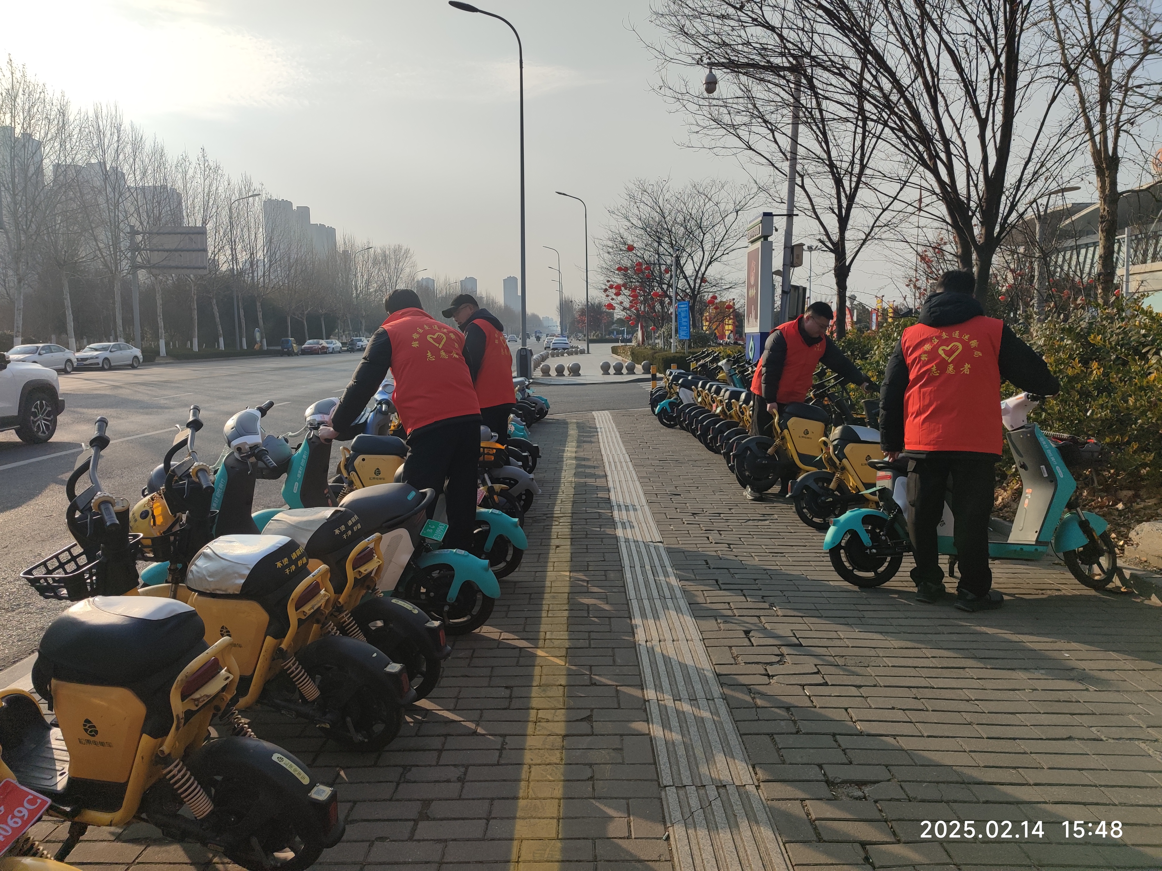 志愿者在站前广场摆放共享电动车.jpg